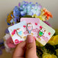 Hand holding cute mini pins in animal parfait style, under natural lighting.