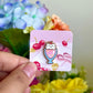Hand holding cat parfait mini pin under natural lighting 