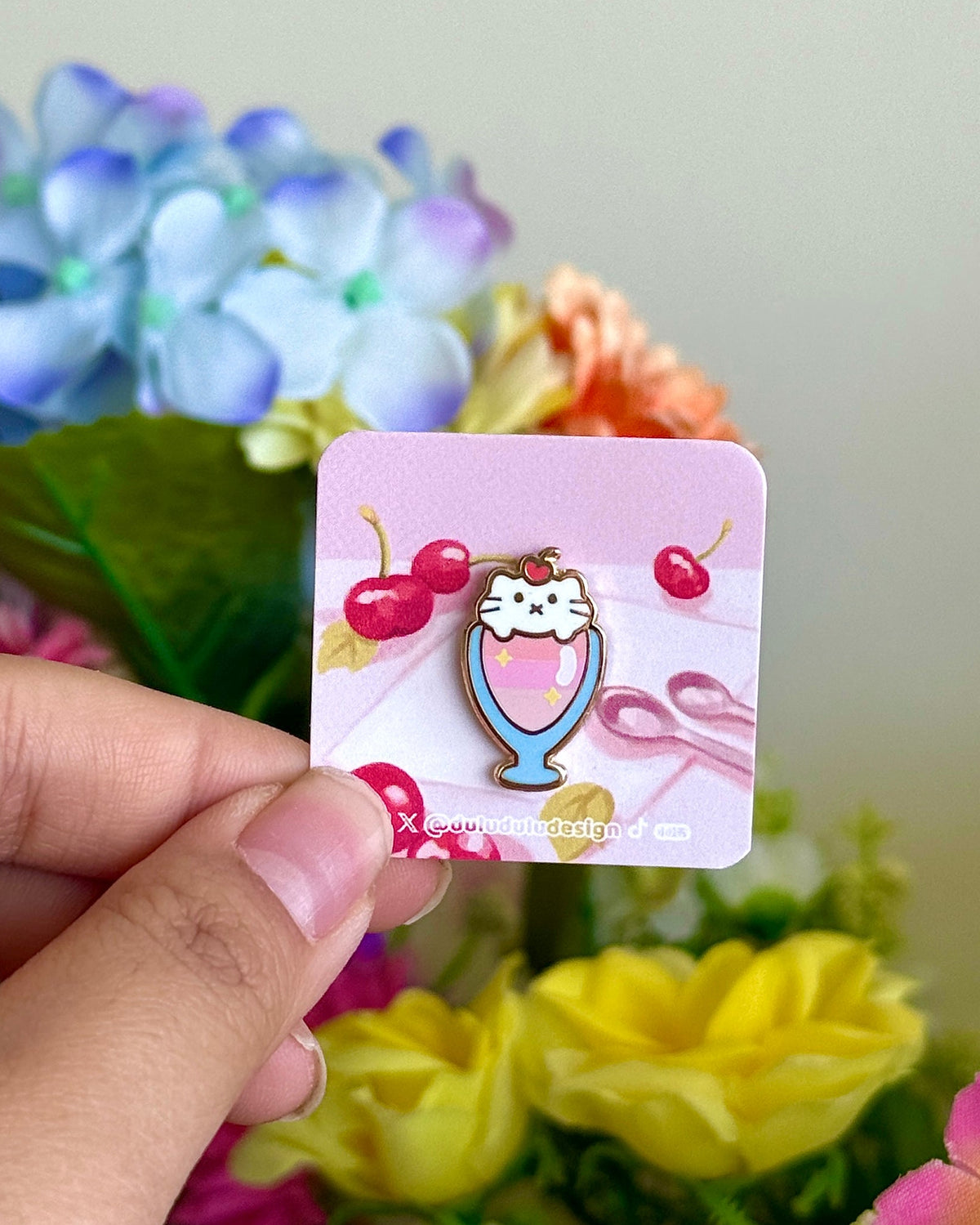 Hand holding cat parfait mini pin under natural lighting 
