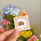 Hand holding croissant mini pin under natural lighting