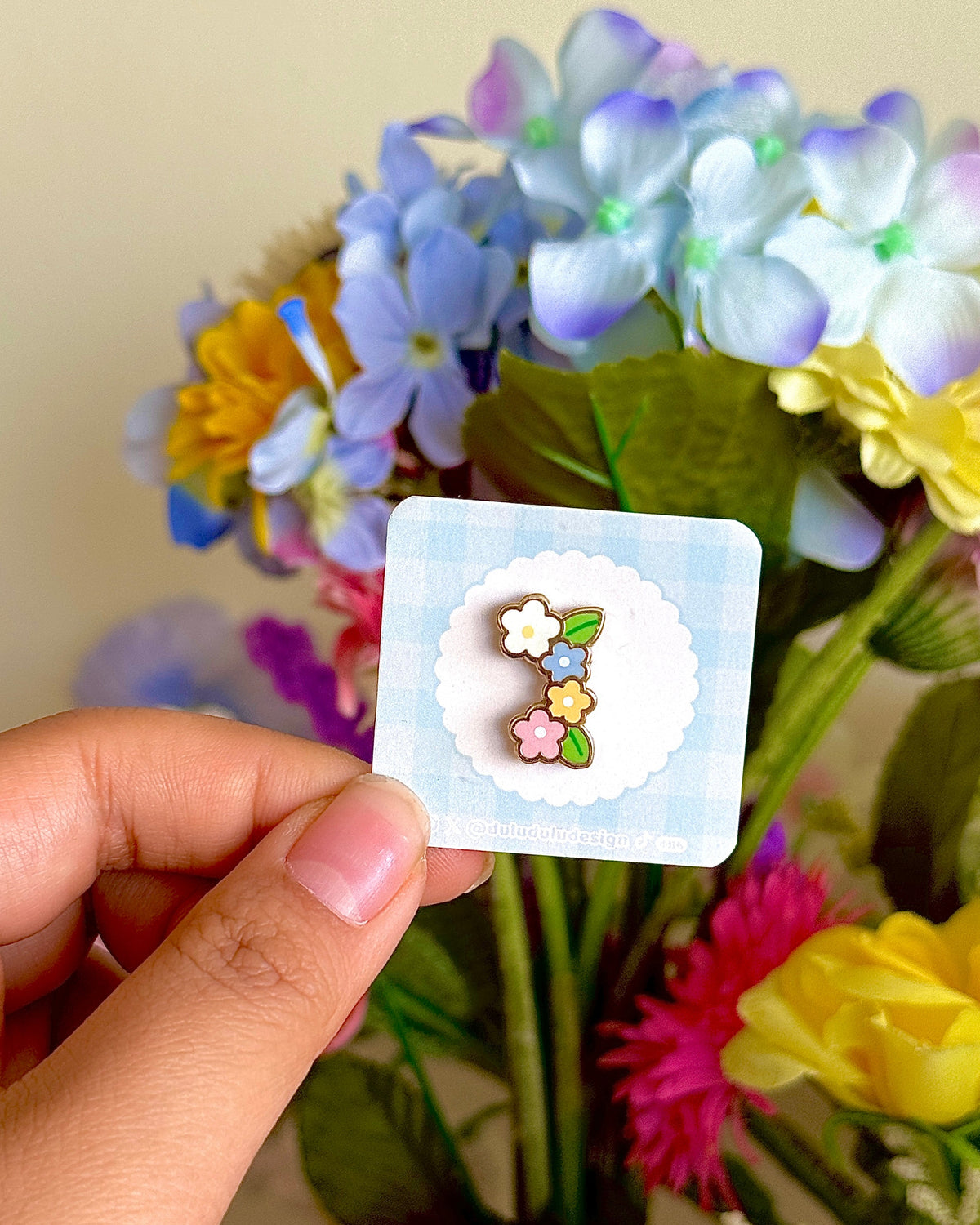 Hand holding a flower mini pin under natural sunlight