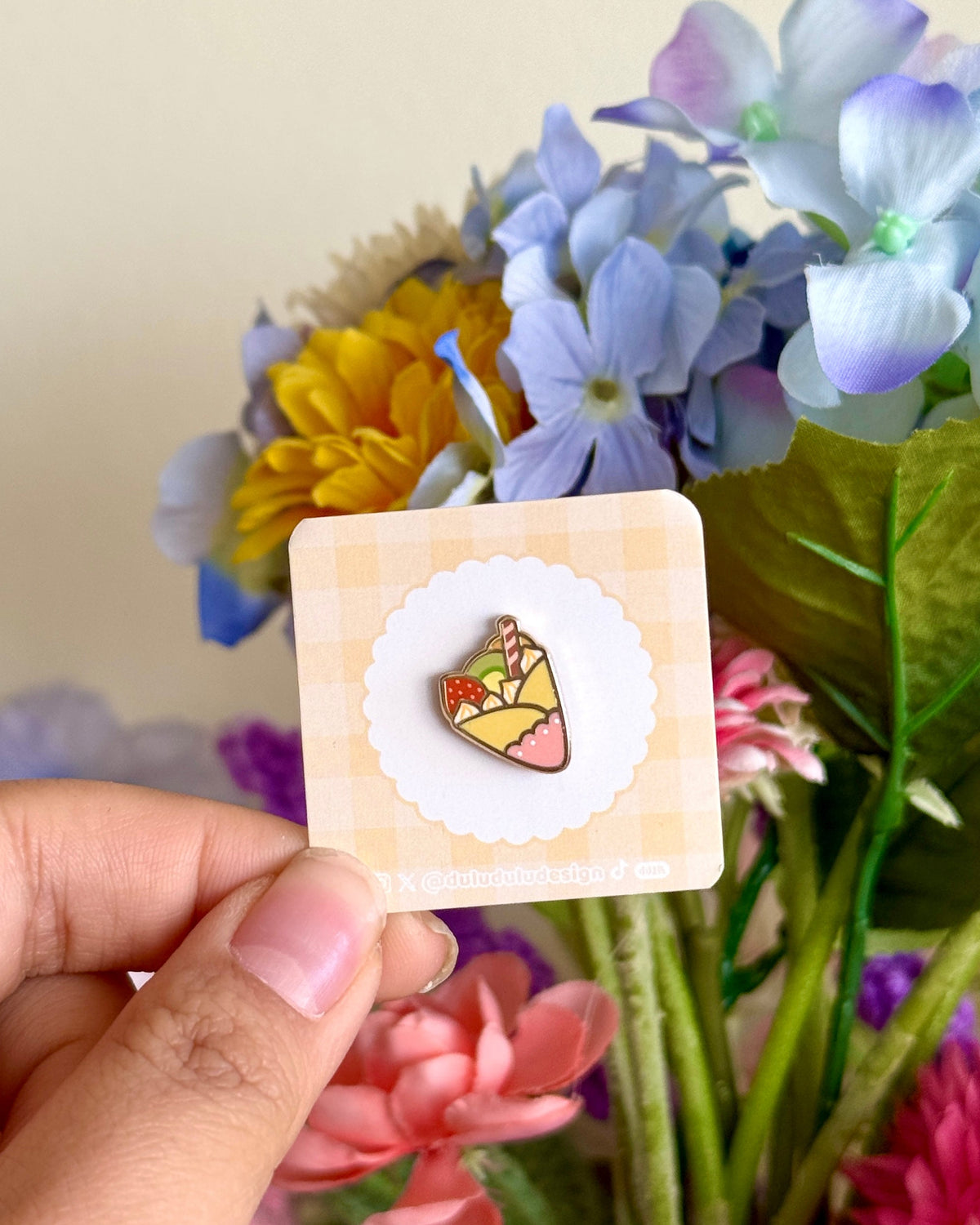 hand holding fruit crepe mini enamel pin under natural sunlight