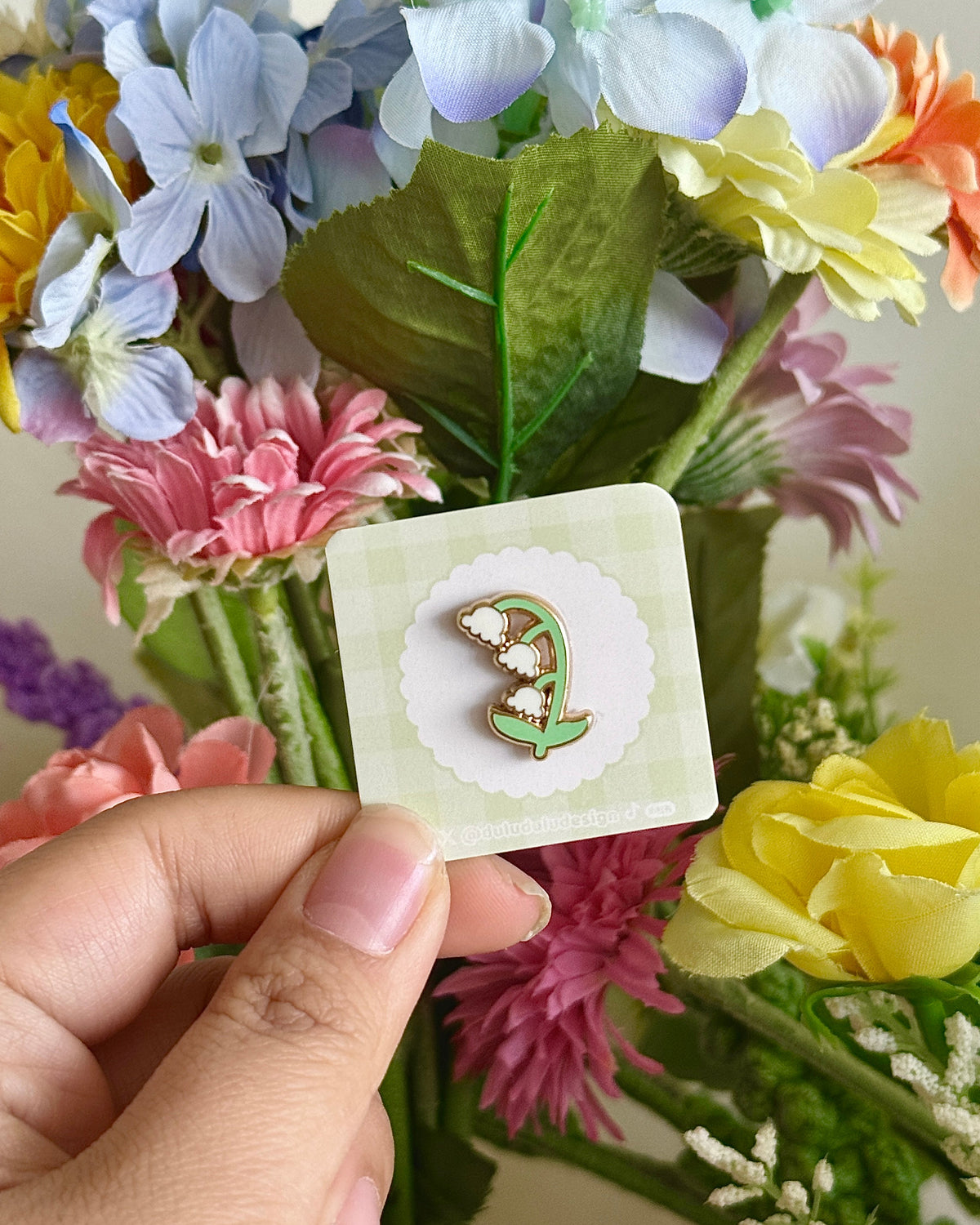 hand holding lily of the valley mini pin under natural lighting