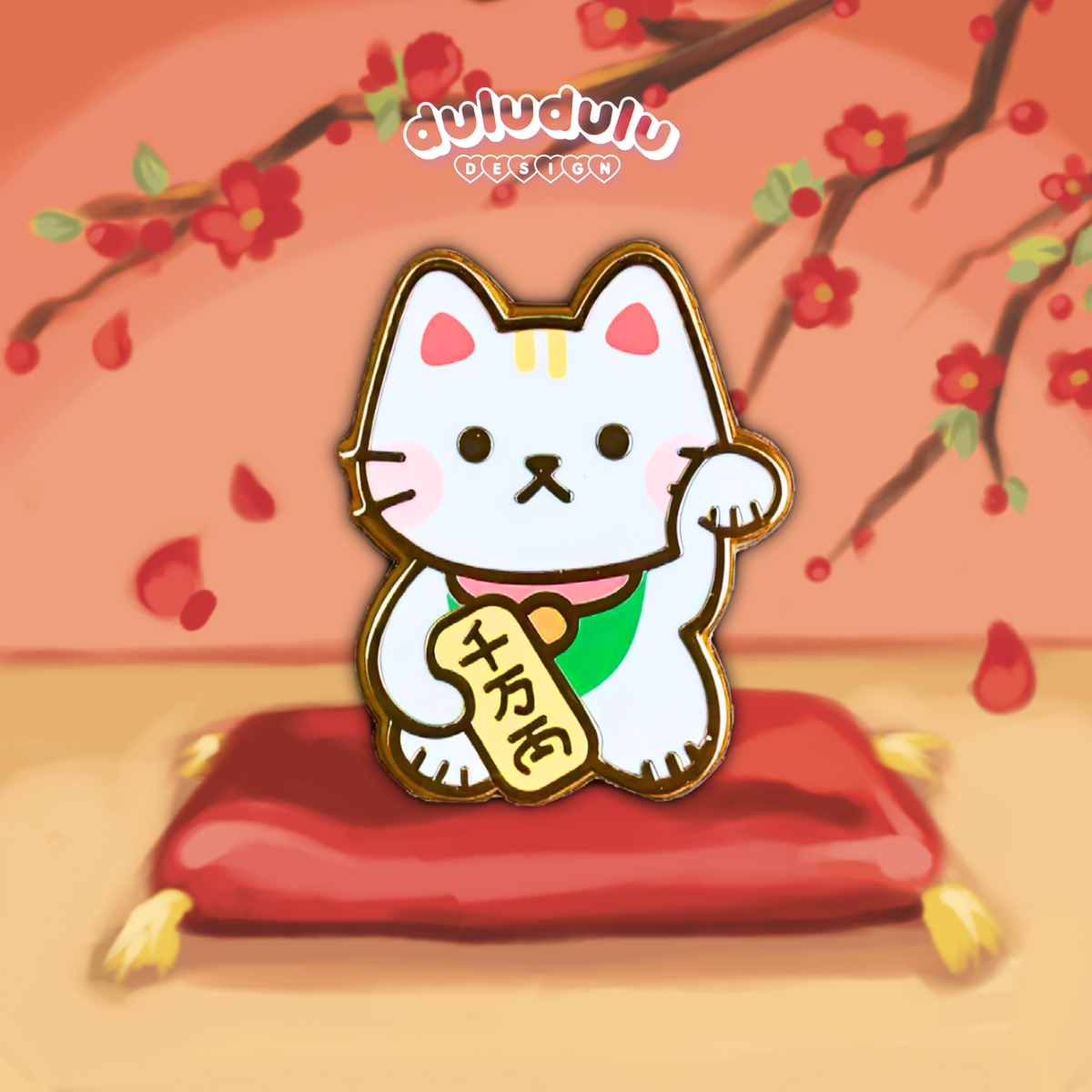 A cartoon-style enamel pin of a lucky cat with one raised paw, holding a gold bar, set against a warm peach background with camellia, sitting on a red cushion.