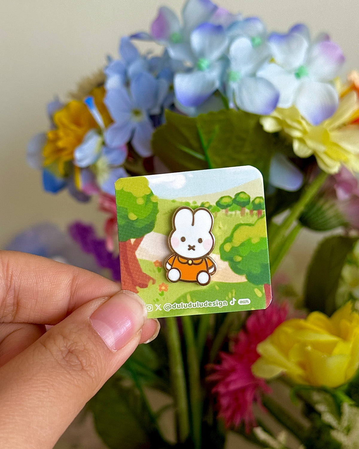 hand holding mini orange miffy pin under natural lighting