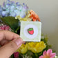 hand holding red strawberry mini pin