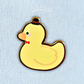 A cute rubber duck enamel pin wearing a bow tie and top hat