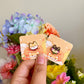 Hand holding both shiba inu pins under natural lighting